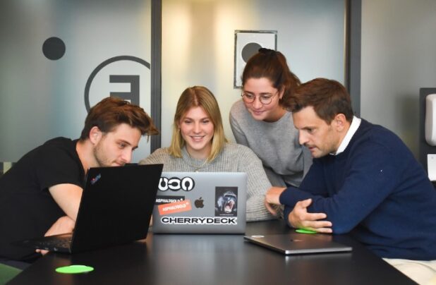 Four people looking at a laptop screen discussing strategic account planning strategies.