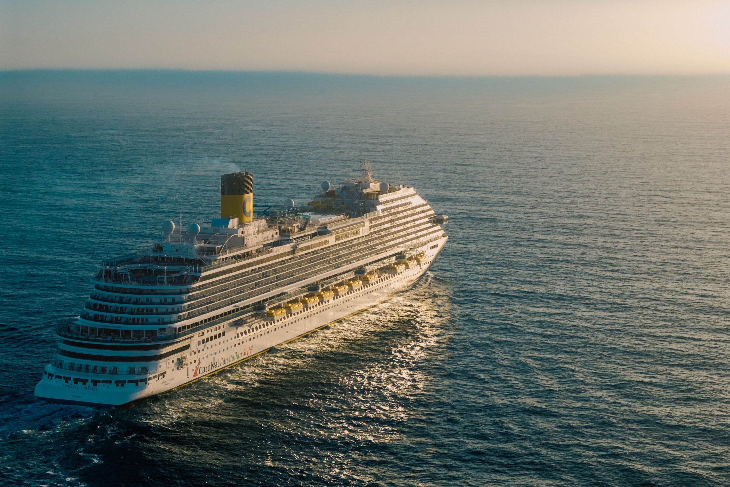 Cruise ship sailing across the ocean at sunset, representing fall 2026 cruise vacations