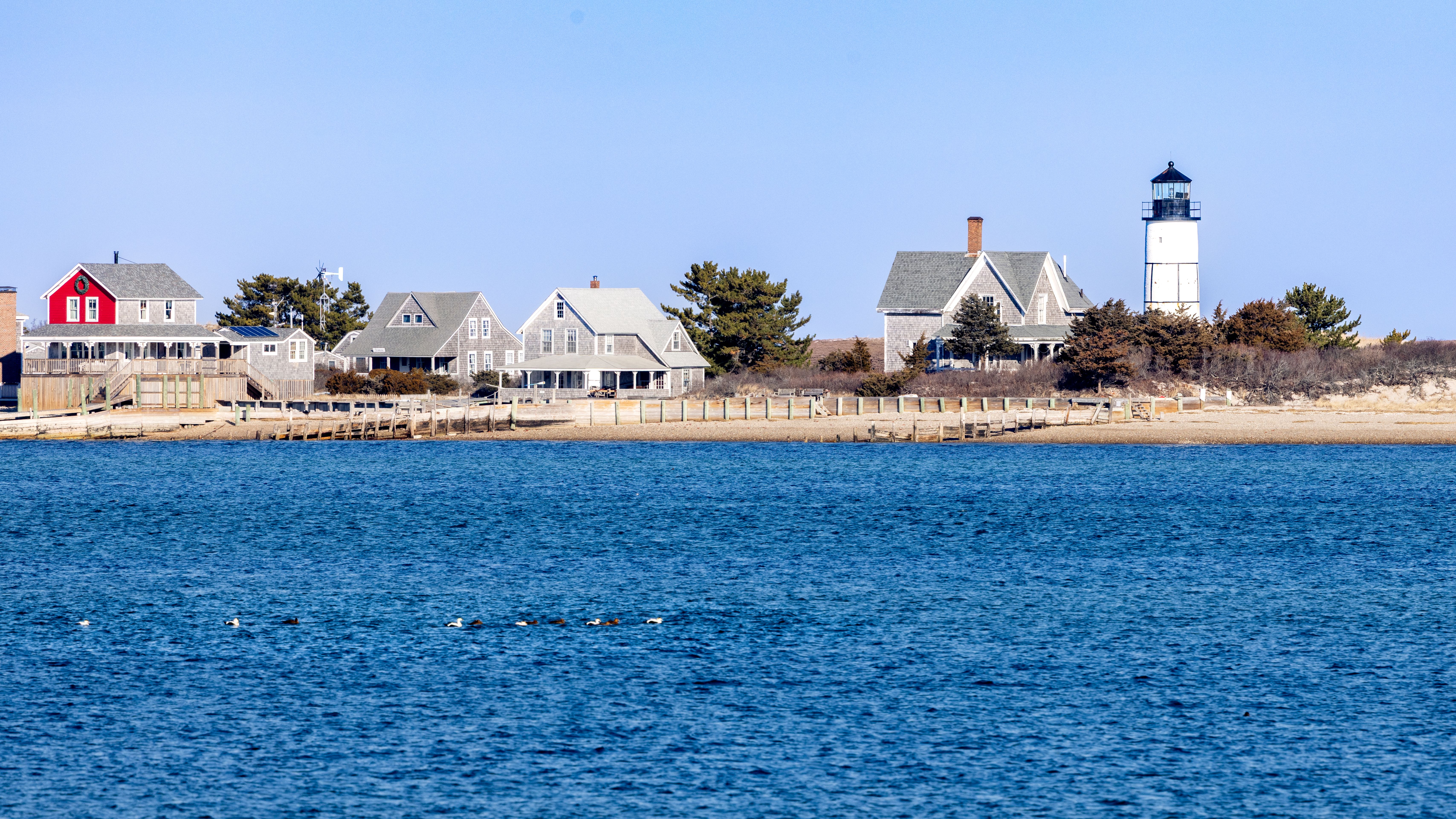 Cape Cod lighthouse and coastal homes on a New England fall foliage cruise