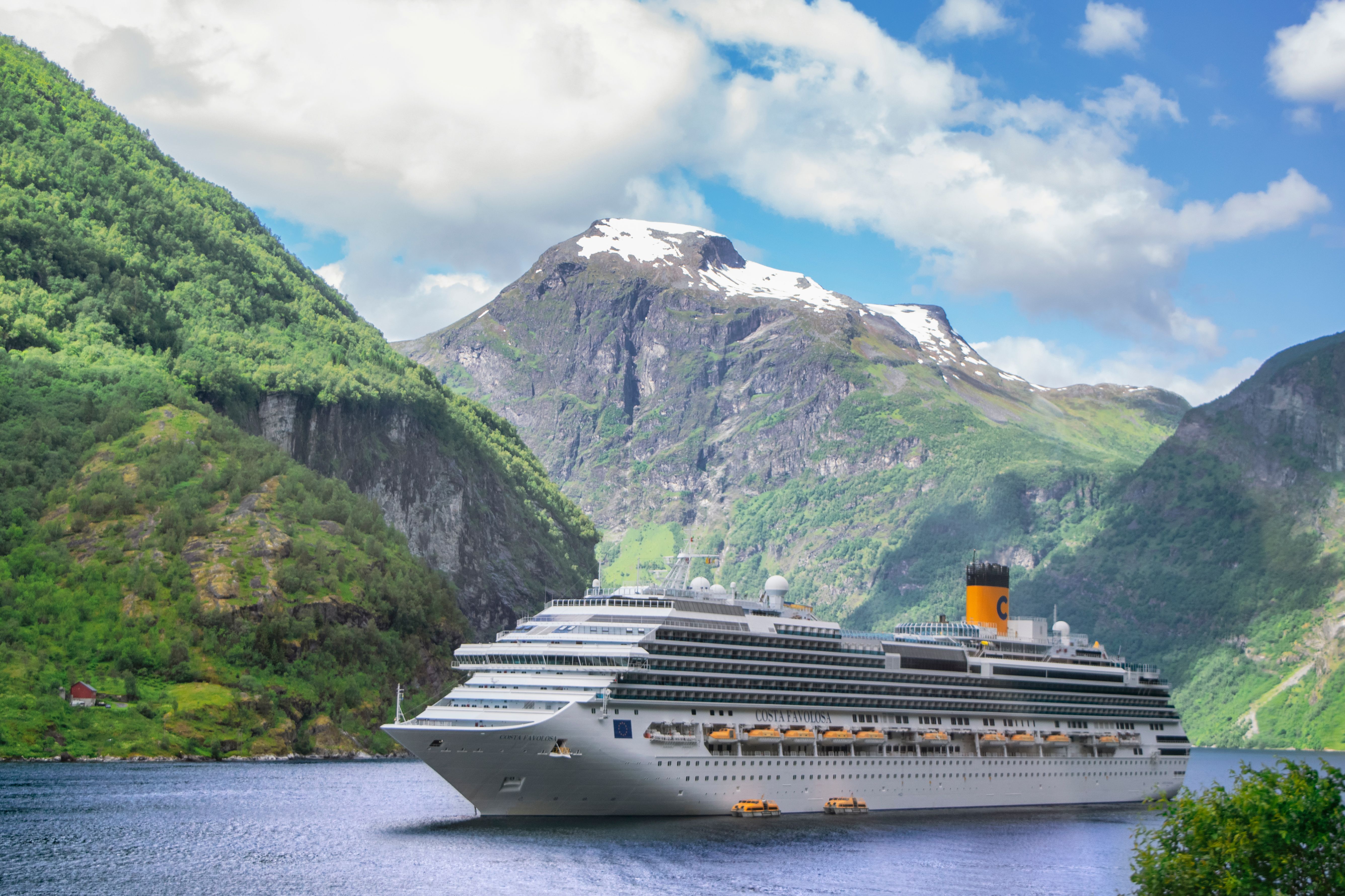 Large cruise ship navigating Geiranger Fjord surrounded by mountains on a Norway fall cruise