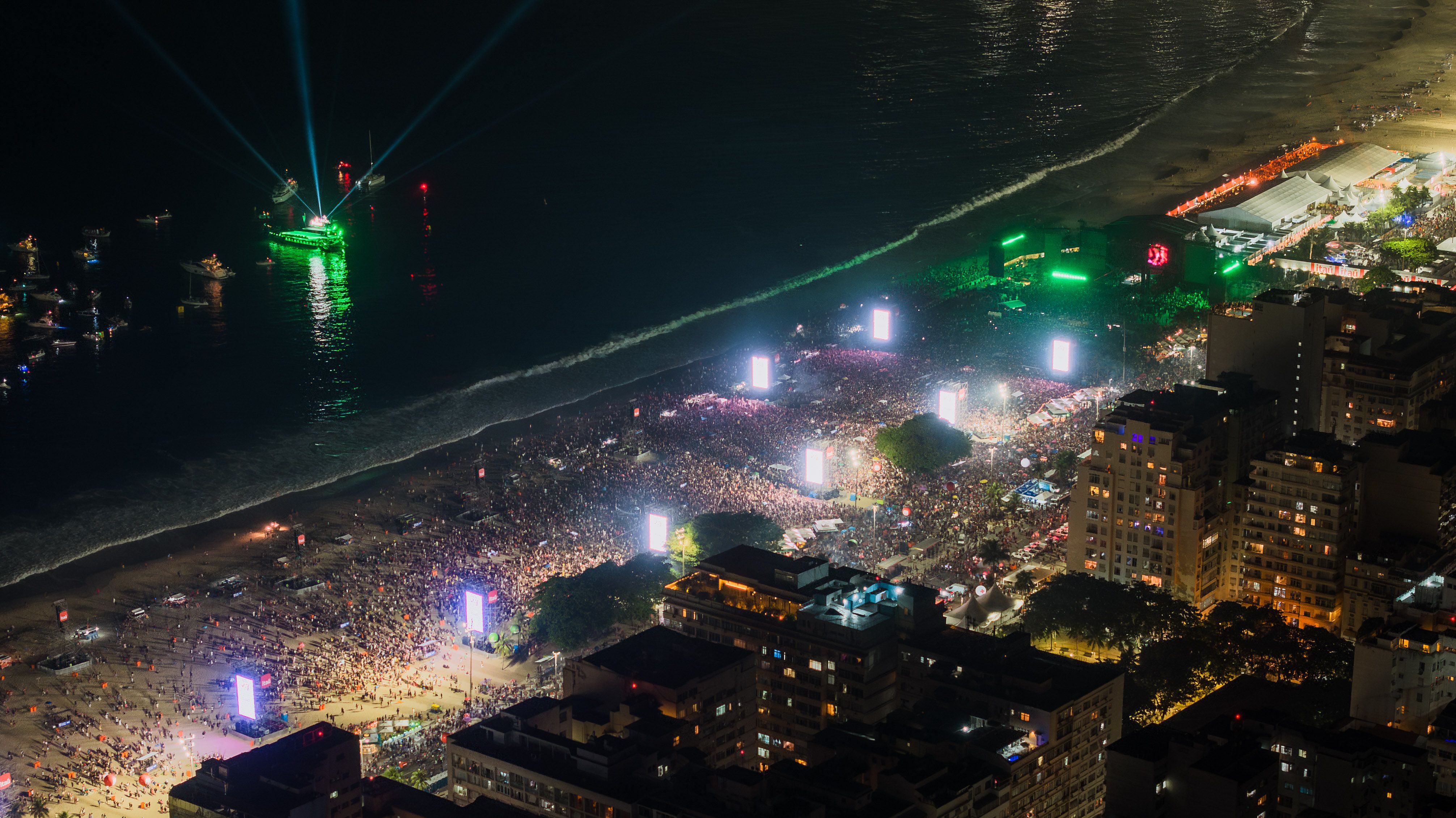 Aerial view of the illuminated crowd celebrating New Year's Eve along Copacabana Beach in Rio de Janeiro